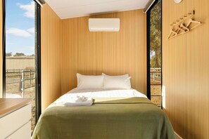 Una habitación con una cama, una ventana y una pared de madera.