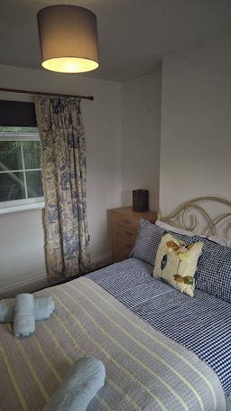 A bedroom with a bed, a bedside table, a lamp, curtains, and a window.. Cool, Calm Georgian Apartment base in Shrewsbury -pet friendly