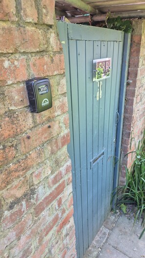 A blue door with a sign, a security device, and a brick wall.