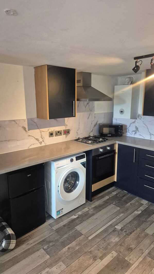 A modern kitchen with a built-in washer, a stove, and a microwave.