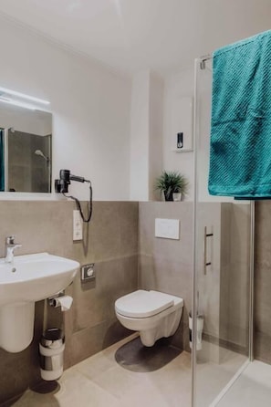 Ein modernes Badezimmer mit Duschkabine aus Glas, einem weißen Waschbecken und einer Toilette.