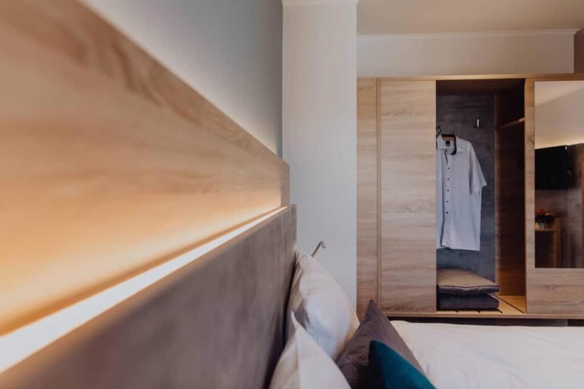 A bedroom with a bed, a wardrobe, and a mirror.