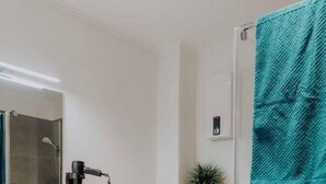 Un baño moderno con cabina de ducha de vidrio, un lavabo blanco y un inodoro.