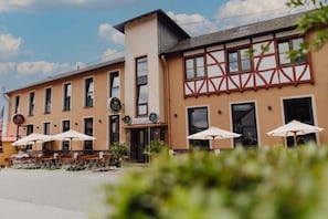 Ein Gebäude mit Restaurant im Erdgeschoss, Außenbereich mit Sonnenschirmen und einem Obergeschoss im Tudorstil.