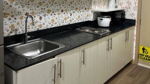 Una cocina con gabinetes blancos, encimera negra, pileta de acero inoxidable y salpicadero con motivos florales.