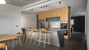 A modern kitchen with wooden cabinets, a central island with bar stools, and a dining area with a wooden table and chairs. - Villa Calvia Crispinilla by Villas Guide (Novigrad)