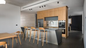 Eine moderne Küche mit Holdekor, einer zentralen Kochinsel mit Barhocker und einem Essbereich mit Holztisch und Stühlen.