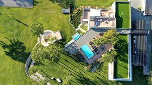 Ein Luftbild eines modernen Hauses mit Schwimmbad, überdachter Terrasse und einer Solaranlage.