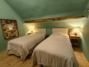 Ein Zimmer mit zwei Einzelbetten, Holzboden und einem Bild an der Wand.