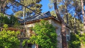 A stone house with a metal roof, surrounded by trees and greenery. - House by the River in Santa María de la Alameda (El Pimpollar)