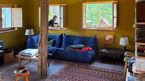 A cozy room with a wooden ceiling, a blue sofa, a patterned rug, and a rustic wooden chair. - House by the River in Santa María de la Alameda (El Pimpollar)