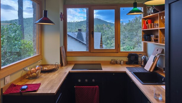 A kitchen with a view of a forested area, wooden countertops, a black stove, and a sink. - House by the River in Santa María de la Alameda (El Pimpollar)