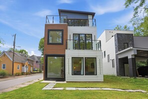 Ein modernes, zweistöckiges Haus mit großen Fenstern, einem Balkon und einer Garage.