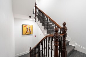 A staircase with wooden balusters and a handrail, a painting on the wall, and a 'no smoking' sign.