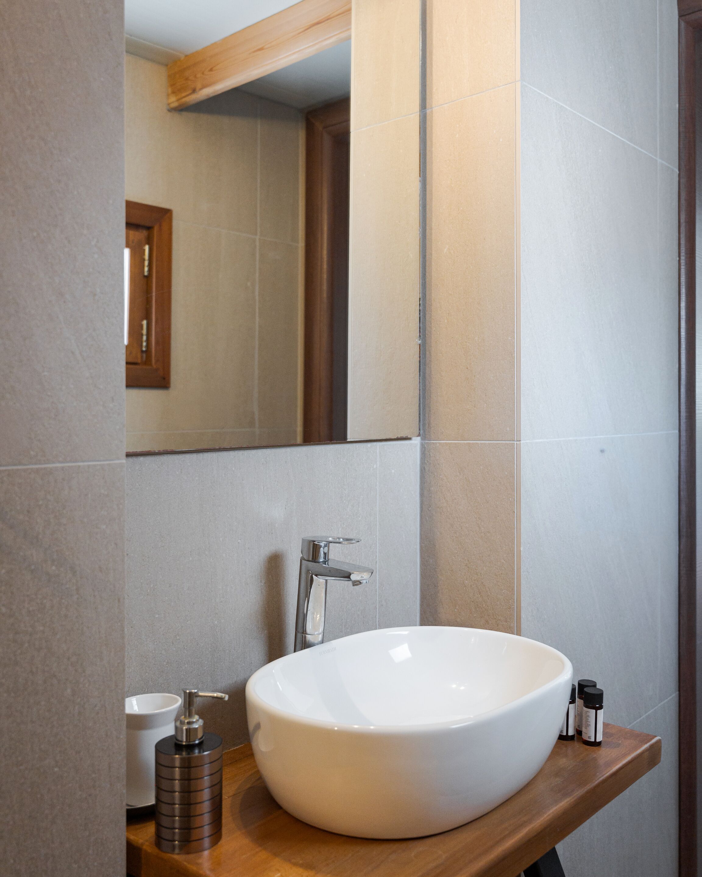 A bathroom with a large white sink, a mirror, and a wooden countertop.