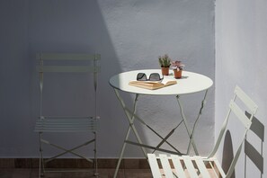 A small round table with a pair of sunglasses, an open book, and two potted plants. - Utopia Suites (Egina)