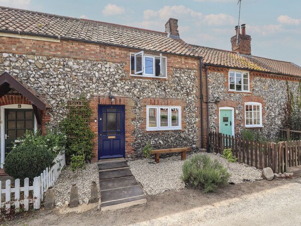 A stone house with a blue door, white windows, and a gravel driveway. - The Monks Retreat (King's Lynn)