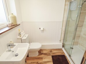 A bathroom with a sink, toilet, and glass shower enclosure. - The Monks Retreat (King's Lynn)