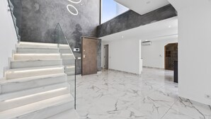 Um interior espaçoso com uma escadaria de mármore, teto alto e amplo espaço aberto.