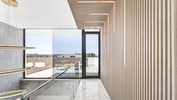 Interior moderno com porta de vidro para um terraço ao ar livre, piso de mármore e teto de madeira ripas.