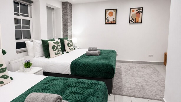 Una habitación de hotel moderna con dos camas, un radiador, una ventana y obras de arte en la pared.