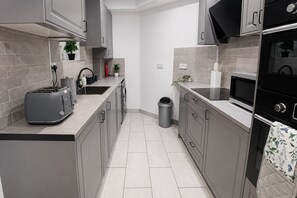 A modern kitchen with grey cabinets, a toaster, a microwave, and a trash bin. - Modern 2-Bedroom flat in Marylebone near Paddington & Edgware Road with Wi-Fi (London)