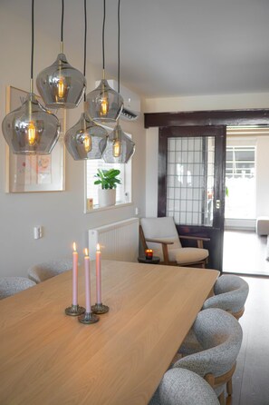 Un coin repas avec une table en bois, quatre chaises et des lampes suspendues.
