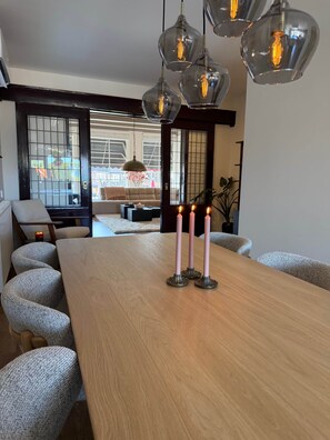 A dining area with a wooden table, three candles, and a view of the outside through a large window.