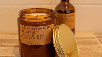A candle with a label, a candle jar, and a bottle with reed sticks.