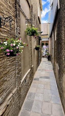 A narrow alleyway with hanging flower baskets and a tiled floor.. Maison Bo | Luxury Stay in Historic Lemmer