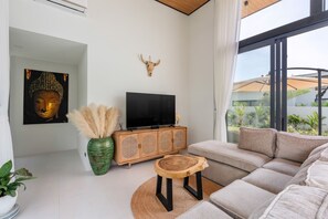 Ein modernes Wohnzimmer mit einer Couch, einem Fernseher auf einer Holzkommode, einem dekorativen Stierkopf und einem Buddha-Gemälde.