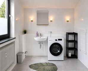 Ett modernt badrum med tvättmaskin, handfat, spegel och element.
