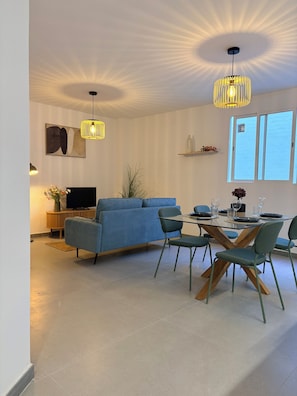 Ein modernes Wohnzimmer mit einer Couch, einem Esstisch, Stühlen und einem Fernseher.