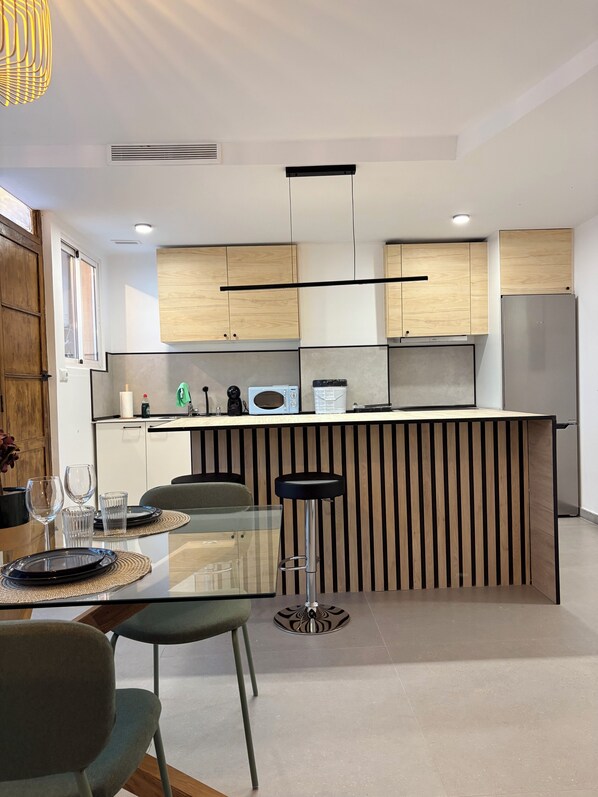 Eine moderne Küche mit Holzausstattung, einem Edelstahlkühlschrank und einer Bar mit Hockern.
