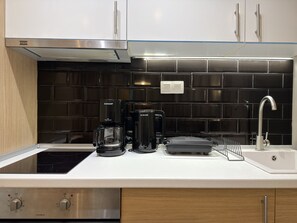 Een keuken met een koffiezetapparaat, een broodrooster, een waterkoker en een spoelbak.