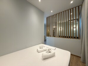 Een hotelkamer met een bed, een raam met verticale zonwering en uitzicht op het interieur.