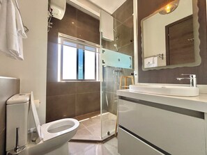 Un baño moderno con inodoro, ducha y lavamanos.