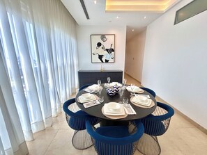 A dining area with a round table, blue upholstered chairs, and a modern ceiling light fixture. - Cozy 2-Bedroom Apartment in Victoria Island, Lagos. (Lagos)