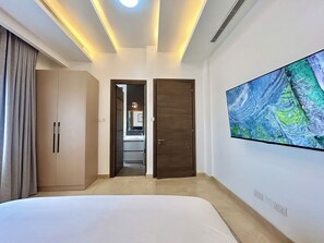 A bedroom with a bed, wardrobe, and a large TV on the wall. - Cozy 2-Bedroom Apartment in Victoria Island, Lagos. (Lagos)