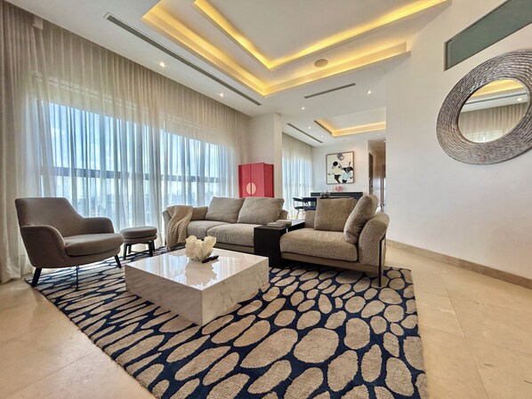 Una sala de estar moderna con un sofá, sillones, una mesita de centro y una alfombra estampada.