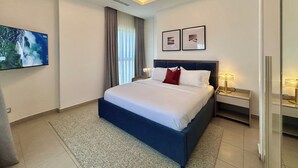Una habitación de hotel moderna con una cama grande, un televisor de pantalla plana, una lámpara de techo y una mesita de noche con lámpara.
