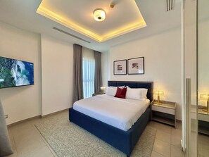 A modern hotel room with a large bed, a flat-screen TV, a ceiling light, and a nightstand with a lamp. - Cozy 2-Bedroom Apartment in Victoria Island, Lagos. (Lagos)