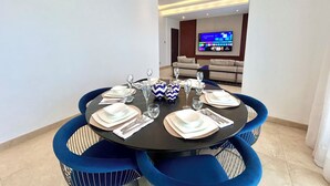 Un comedor con una mesa redonda dispuesta para seis personas, rodeada de sillas tapizadas en azul.