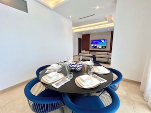 A dining area with a round table set for six, surrounded by blue upholstered chairs. - Cozy 2-Bedroom Apartment in Victoria Island, Lagos. (Lagos)