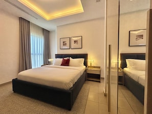 Ein Hotelzimmer mit einem großen Bett, Nachttischen, einem Spiegel und gerahmten Bildern an der Wand.
