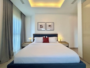 Ein Hotelzimmer mit einem großen Bett, zwei Nachttischen, einer Deckenleuchte und zwei gerahmten Bildern an der Wand.