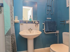 Ein Badezimmer mit Waschbecken, Spiegel, Handtuchhalter und Toilette.
