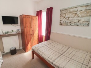A bedroom with a bed, a wardrobe, a radiator, a TV, and a wall art piece. - Meltham Guest House (Scarborough)