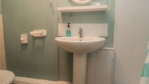 A bathroom with a white sink, a mirror, and a toilet. - Meltham Guest House (Scarborough)