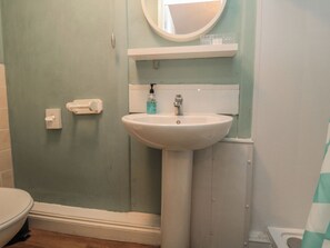 A bathroom with a white sink, a mirror, and a toilet. - Meltham Guest House (Scarborough)
